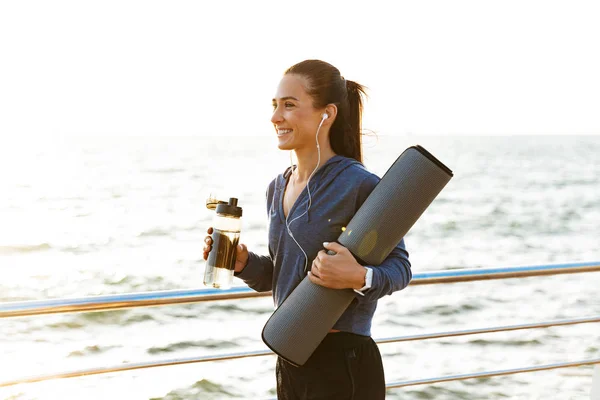 Deportista Sonriente Caminando Por Playa Llevando Tapete Fitness — Foto de Stock