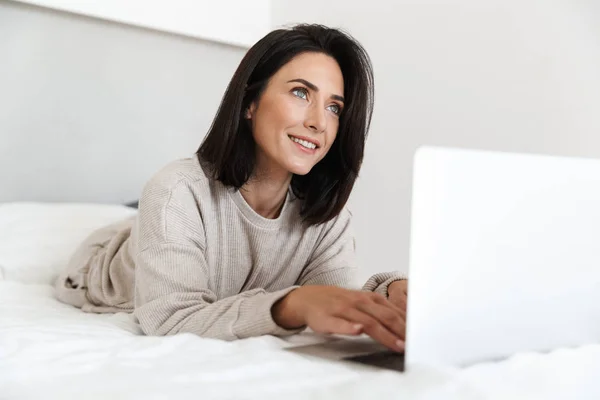 Photo Adorable Woman 30S Using Laptop While Lying Bed White — Stock Photo, Image