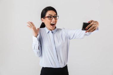 Mutlu heyecanlı işkadını akıllıca bir selfie alarak ayakta beyaz arka plan üzerinde izole giyinmiş