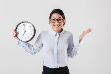 Mutlu heyecanlı işkadını akıllıca giyinmiş ayakta beyaz arka plan üzerinde izole çalar saat gösterilen