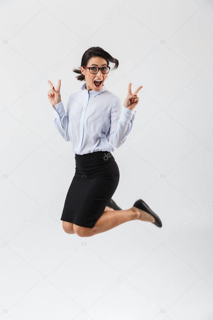 Full length portrait of a pretty businesswoman jumping isolated over white background, celebrating success