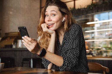 Kapalı cep telefonu arkadaşlarınızla konuşurken kullanarak kafede oturan duygusal mutlu güzel genç güzel kadın fotoğrafını çekin bir selfie.