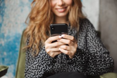 Kapalı cep telefonu sohbet kullanarak kafede oturan güzel genç güzel kadın Resim kırpılmış.