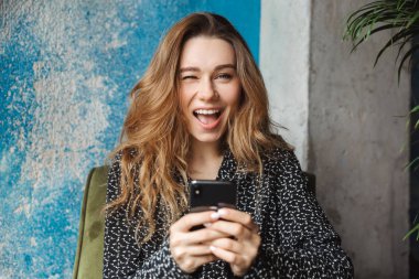 Kapalı cep telefonu sohbet kullanarak kafede oturan güzel genç güzel kadın fotoğrafı.