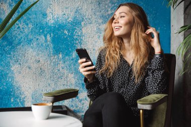 Kapalı cep telefonu sohbet kullanarak kafede oturan güzel genç güzel kadın fotoğrafı.