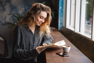 Kahve içme kafede kapalı, kitap okumak, oturan güzel genç kadın