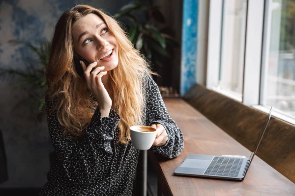 Фото Счастливой Красивой Молодой Женщины Сидящей Кафе Помещении Разговаривающей Мобильному — стоковое фото