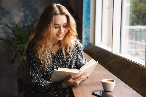 Schöne Junge Frau Sitzt Café Drinnen Liest Buch Trinkt Kaffee — Stockfoto