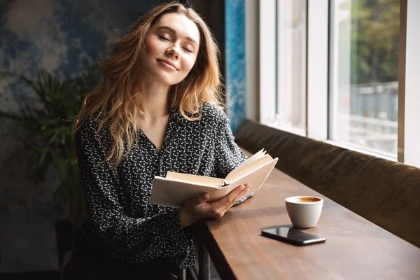 Красивая Молодая Женщина Сидит Кафе Помещении Читает Книги Пьет Кофе — стоковое фото