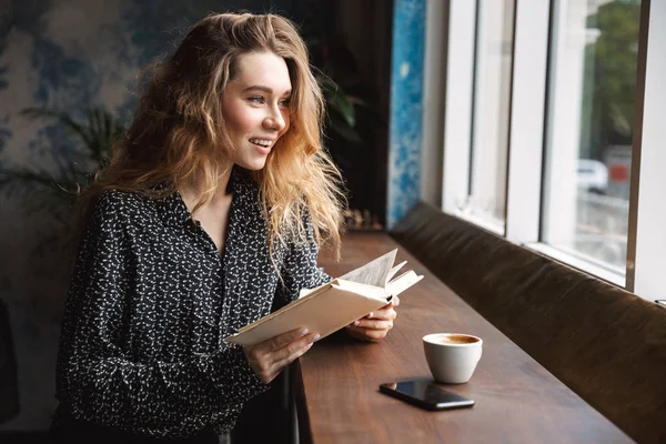 Schöne Junge Frau Sitzt Café Drinnen Liest Buch Trinkt Kaffee — Stockfoto