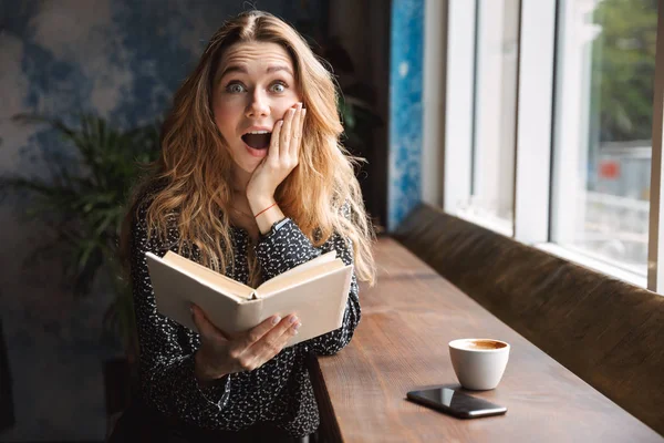 Hermosa Mujer Joven Emocionada Sentada Café Interior Libro Lectura Beber — Foto de Stock
