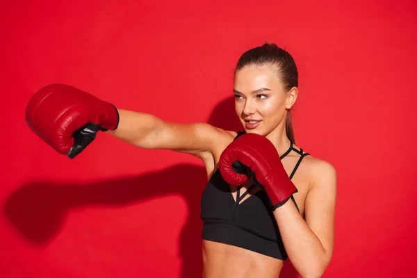 一个美丽的年轻快乐开朗的健身拳击手妇女摆在红色墙壁背景孤立使锻炼手套的图像 — 图库照片