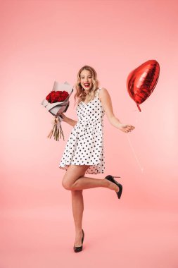 Buket gül ve kalp tutan pembe arka plan üzerinde izole ayakta elbise güzel genç sarışın bir kadın portresi tam uzunlukta balon şeklinde