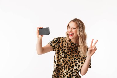 Bir selfie alarak beyaz arka plan üzerinde izole ayakta çekici bir genç sarışın kadın portresi