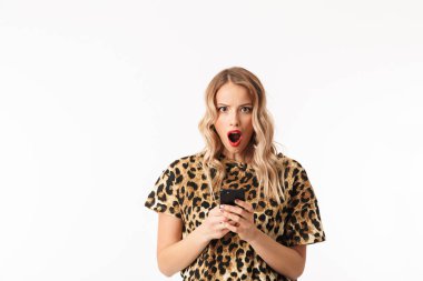 Cep telefonu tutan beyaz arka plan üzerinde izole ayakta çekici bir şok genç sarışın kadın portresi