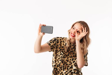 Bir selfie alarak beyaz arka plan üzerinde izole ayakta çekici bir genç sarışın kadın portresi