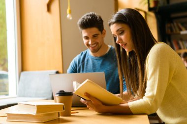 Fotoğraf kitaplığındaki okumak ev ödevi eğitim ve dizüstü bilgisayar kullanan bir iki genç öğrenci arkadaşlar çiftin.
