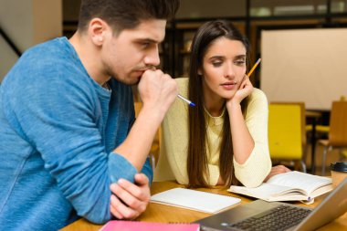 Fotoğraf kitaplığındaki okumak ev ödevi eğitim ve dizüstü bilgisayar kullanan bir iki genç öğrenci arkadaşlar çiftin.