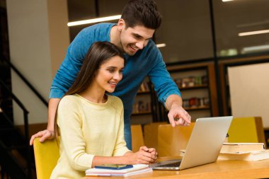 Fotoğraf kitaplığındaki okumak ev ödevi eğitim ve dizüstü bilgisayar kullanan bir iki genç öğrenci arkadaşlar çiftin.