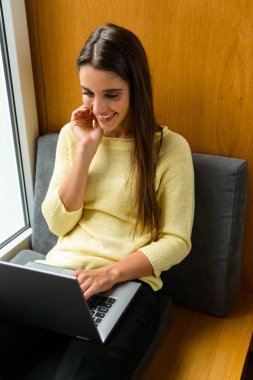 Resim kitaplığındaki dizüstü bilgisayar kullanan bir genç öğrenci konsantre kadının.