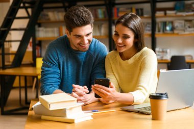 Birbirleri ile cep telefonuyla konuşan kitaplık eğitim genç öğrenciler arkadaş Çift.