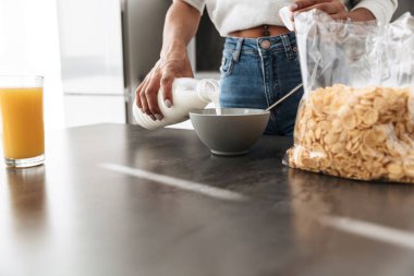 Kahvaltı Mısır gevreği ve süt ile şık mutfak yapmak memnun Afrikalı-Amerikalı kadın görüntüsünü