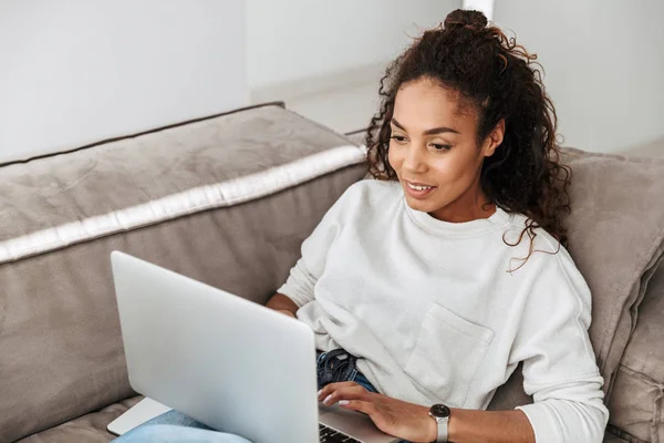 Photo Satisfied African American Woman Using Laptop While Lying Sofa — Stock Photo, Image