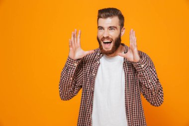 Çığlık sarı arka plan üzerinde izole ayakta rahat kıyafetler giymiş neşeli genç bir adam portresi
