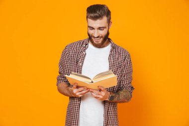 Kağıt kitap sarı arka plan üzerinde izole ayakta rahat kıyafetler giymiş neşeli genç bir adam portresi