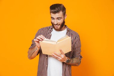 Kağıt kitap sarı arka plan üzerinde izole ayakta rahat kıyafetler giymiş neşeli genç bir adam portresi