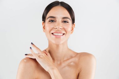 Omzunda nemlendirici uygulayarak beyaz arka plan üzerinde izole duran bir çekici sağlıklı kadın Güzellik Portresi