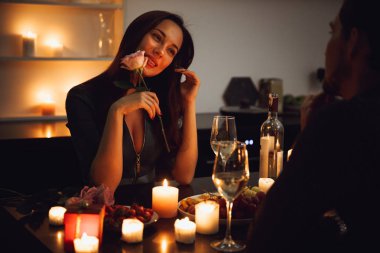 Evde, bir mum ışığında romantik akşam yemeği güzel tutkulu çift bir çiçek kokulu kadın