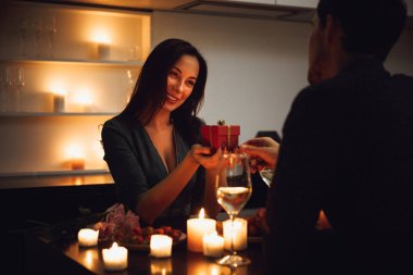 Bir mum ışığında romantik akşam evde, şarap, kadın bir hediye kutusu alma içme yemeği güzel tutkulu Çift