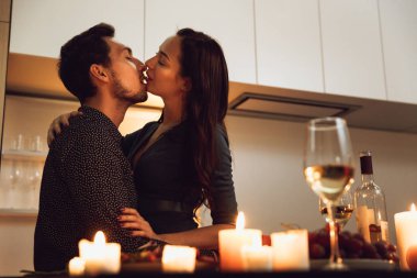 Evde mum ışığında romantik bir akşam yemeği, öpüşme güzel tutkulu Çift
