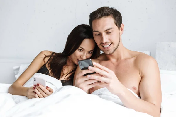 Schönes Junges Paar Liegt Bett Und Hält Mobiltelefone Der Hand — Stockfoto