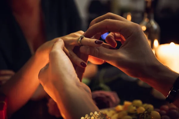 在浪漫晚餐时 一个男人把订婚戒指戴在女人的手指上 — 图库照片