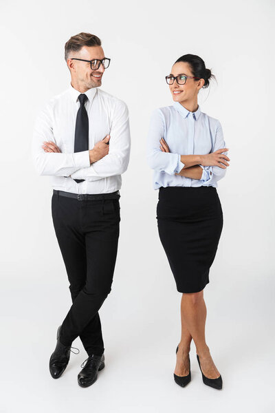 Full length of a confident colleagues couple wearing formal clothing standing isolated over white background, arms folded