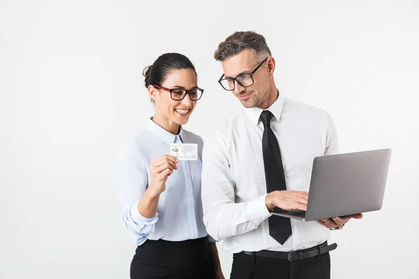 クレジット カード提示のラップトップを保持しているフォーマルな服立っている白い背景に分離された身に着けている同僚のカップル — ストック写真
