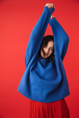 Güzel bir genç kadının poz fotoğraf izole kırmızı duvar arka plan üzerinde.