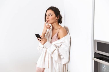 Güzel kadın 20'li yaşlarda fotoğrafı evde mutfakta dururken kulaklık kullanarak