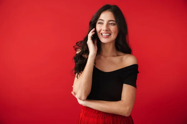 携帯電話で話している赤い壁背景に分離立って美しい幸せな若い女性の写真 — ストック写真