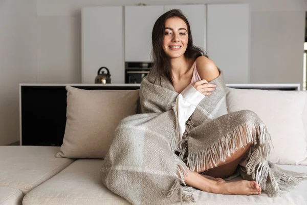 Φωτογραφία Ευτυχισμένη Γυναίκα 20S Τυλιγμένο Κουβέρτα Που Κάθεται Στον Καναπέ — Φωτογραφία Αρχείου