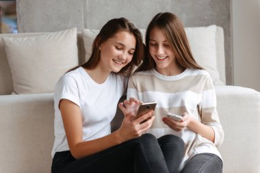 İki güzel genç genç kız cep telefonunu kullanarak