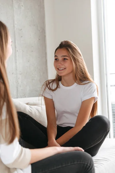 Twee vrolijke meisjes praten tijdens het om thuis te zitten — Stockfoto