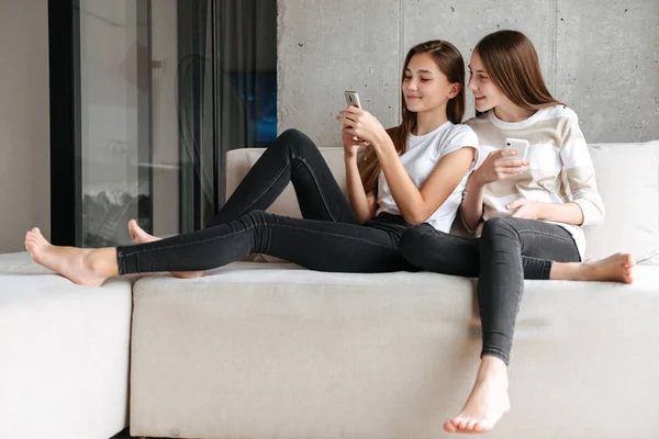 Дві веселі подруги-підлітки тримають мобільні телефони — стокове фото