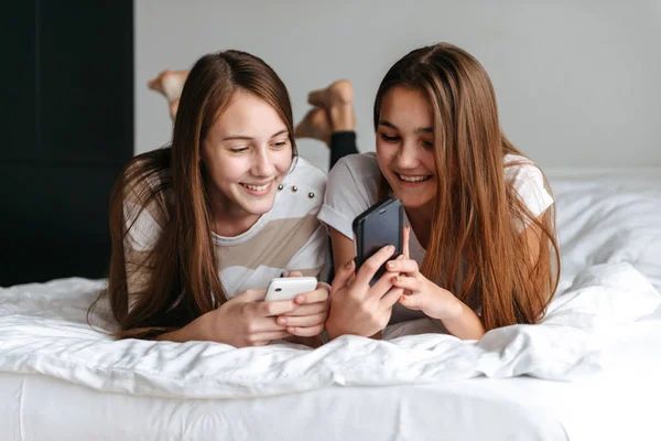 Две милые улыбающиеся девочки-подростки лежат на кровати — стоковое фото