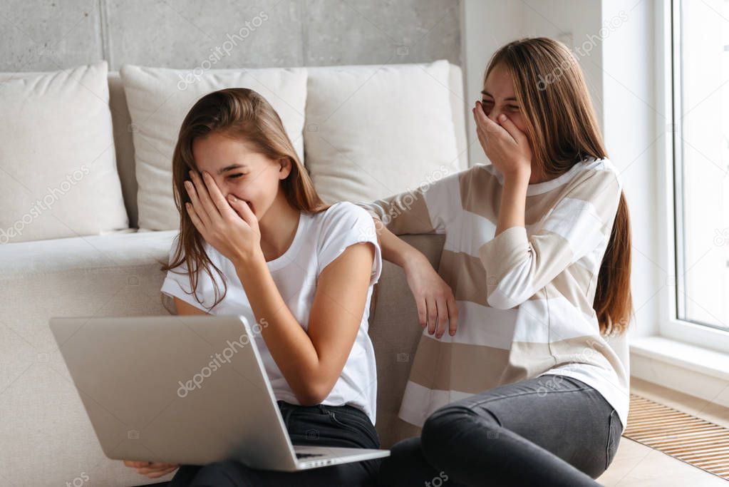 Two lovely cheerful young teenage girls using laptop