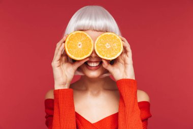 Güzel genç kadın turuncu tutan kırmızı duvar arka plan üzerinde izole.