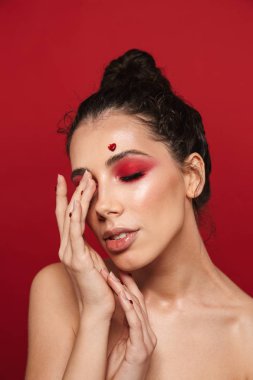 Kadının yüzündeki yürekleri poz kırmızı duvar arka plan üzerinde izole kırmızı parlak makyaj ile.