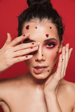 Kadının yüzündeki yürekleri poz kırmızı duvar arka plan üzerinde izole kırmızı parlak makyaj ile.
